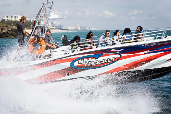Speedboat named Sea Rocket with tourists on ocean, splashing water.