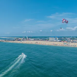 a group of people flying kites on a beach near a body of water