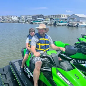 a person riding a motorcycle with a boat in the water