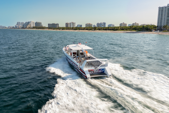 Speedboat cruising along the ocean with city skyline in the background.