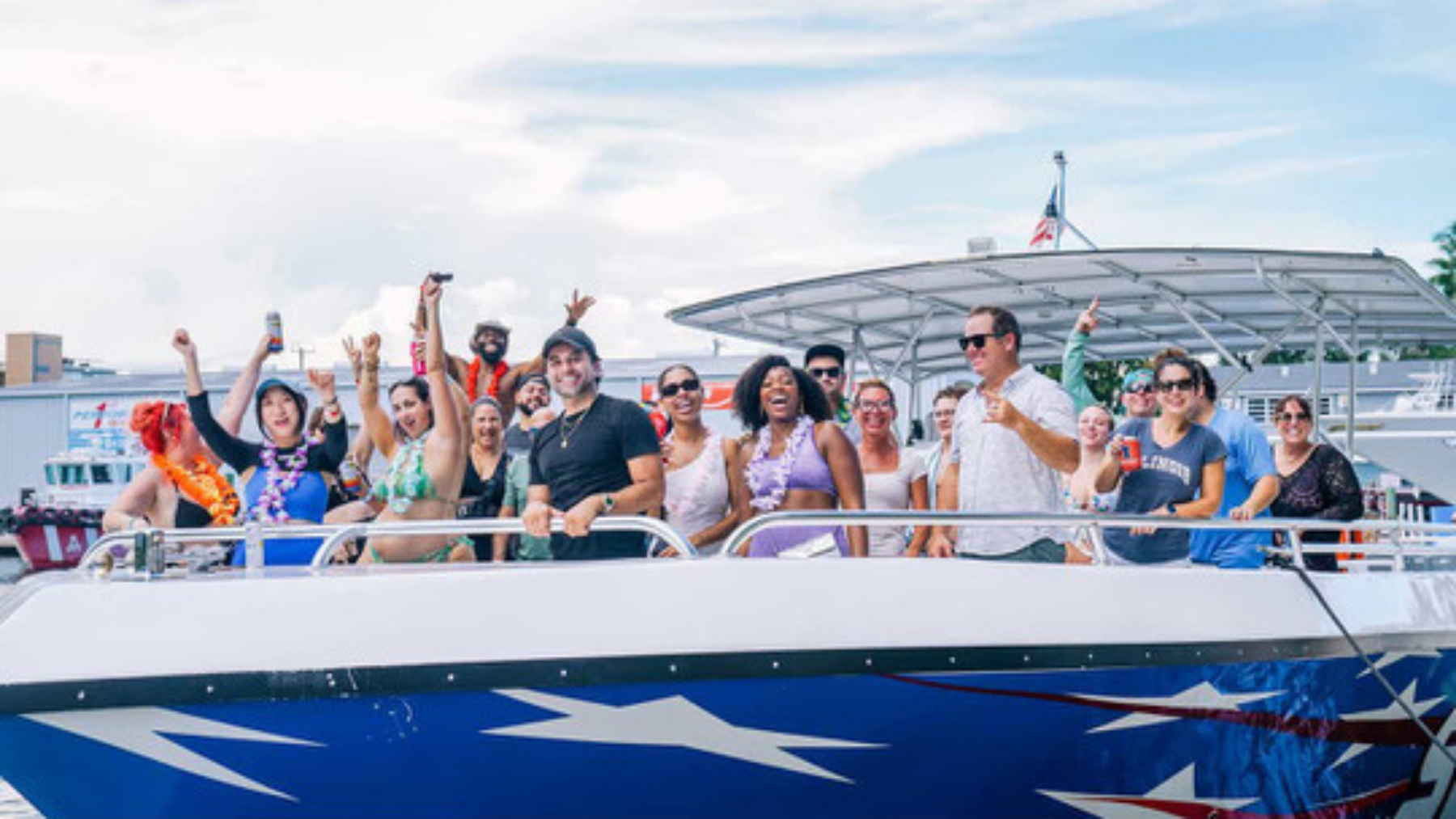 Group of people enjoying a boat ride, smiling and waving.